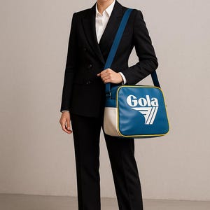 May include: A woman in a black suit and white shirt carries a blue, white, and yellow Gola shoulder bag. The bag has a rectangular shape with the Gola logo in white. The woman is wearing black heels.