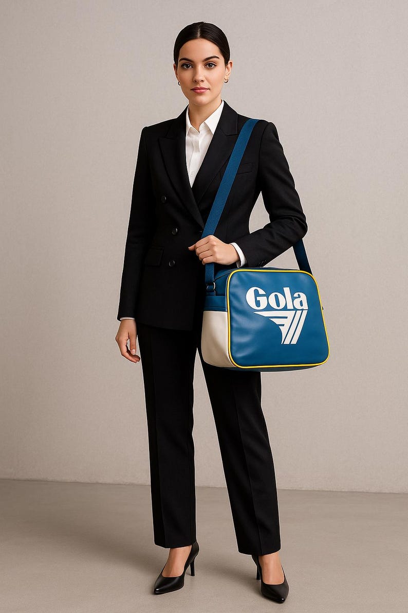 May include: A woman in a black suit and white shirt carries a blue, white, and yellow Gola shoulder bag. The bag has a rectangular shape with the Gola logo in white. The woman is wearing black heels.