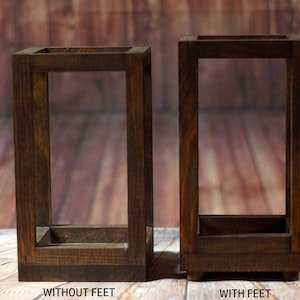 May include: Two wooden rectangular frames, one with feet and one without. Both frames are made of dark brown wood and have a simple design.