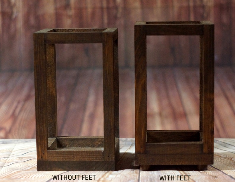 May include: Two wooden rectangular frames, one with feet and one without. Both frames are made of dark brown wood and have a simple design.