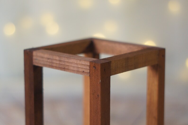 May include: A wooden square frame made of light brown wood. The frame is empty and has a smooth finish.