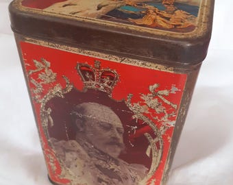 May include: Vintage rectangular tin with a red background and a portrait of a man wearing a crown. The tin has a brown border and gold accents. The top of the tin features a painting of a person wearing a crown.
