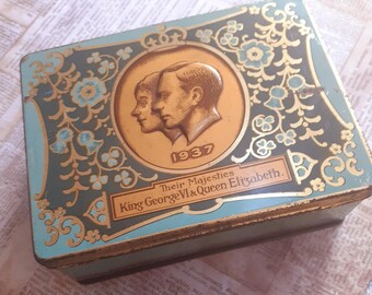 May include: Vintage rectangular tin box with a teal and gold floral design. The box features a gold medallion with profiles of King George VI and Queen Elizabeth, and the year 1937. The text "Their Majesties King George VI & Queen Elizabeth" is also visible.