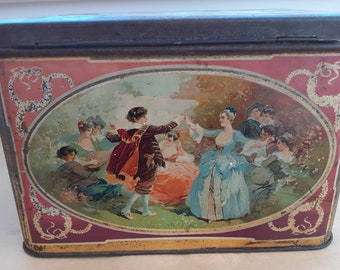 May include: A vintage tin box with a colorful illustration of people dancing in a garden. The box has a red background with gold accents and a white oval frame around the illustration.