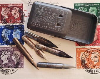 May include: A vintage metal Perry & Co. London patent case for pens and pencils, accompanied by four assorted metal dip pen nibs. The case features engraved text and geometric patterns, resting on a background of vintage postage stamps.