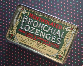 May include: A rectangular metal tin for Mentholated Bronchial Lozenges by Parke, Davis & Company, Limited. The green and cream label features silver embossed lettering, decorative scrollwork, and a list of ingredients including menthol and anise.