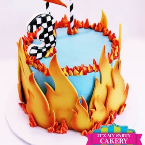 May include: A blue and orange birthday cake decorated with flames and a checkered number three. The cake has a topper that says "Lalito" with a flame design.