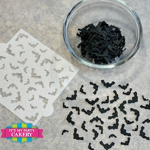 May include: A white stencil with a repeating pattern of bats, a bowl filled with black bat cutouts, and a scattering of black bat cutouts on a white surface. The text "It'z My Party Cakery" is printed on a blue, green, and yellow banner.