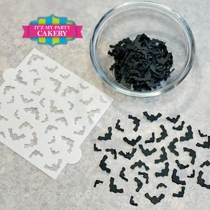 May include: A white stencil with a repeating pattern of bats, a bowl of black bat sprinkles, and a scattering of black bat sprinkles on a gray surface. The stencil is labeled "It'z My Party Cakery".