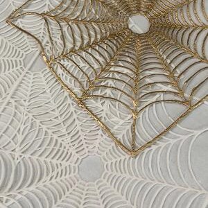 May include: A white and gold spiderweb design with a raised texture. The design is made of two layers, one on top of the other. The top layer is gold and the bottom layer is white.