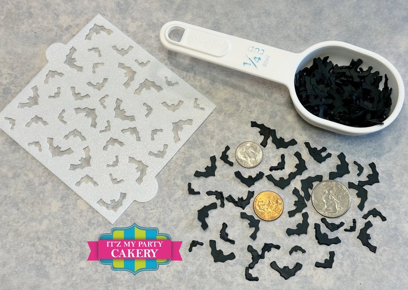 May include: A white stencil with a bat pattern, a white measuring cup filled with black bat confetti, and a pile of black bat confetti on a gray surface. The measuring cup has the text "1/4 cup" printed on it. The text "IT'Z MY PARTY CAKERY" is printed on a colorful ribbon.