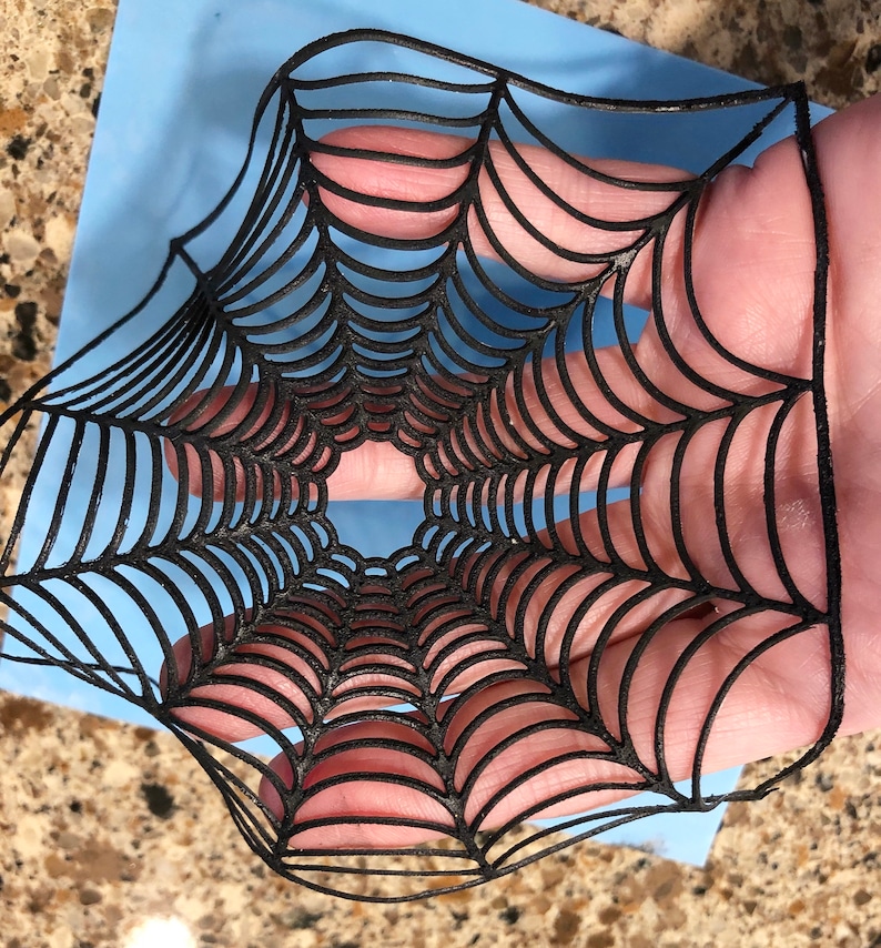 May include: Black spiderweb cutout, a decorative element for Halloween crafts and decorations.