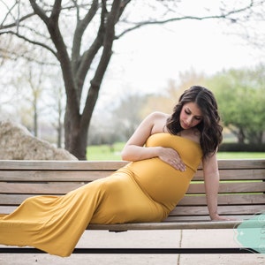 The Aphrodite strapless maternity gown is fitted in a mermaid design that flares at the bottom in a long train. Perfect for special occasions, the soft knit dress hugs your curves and bump in all the right places. Comes in many colors & plus sizes.