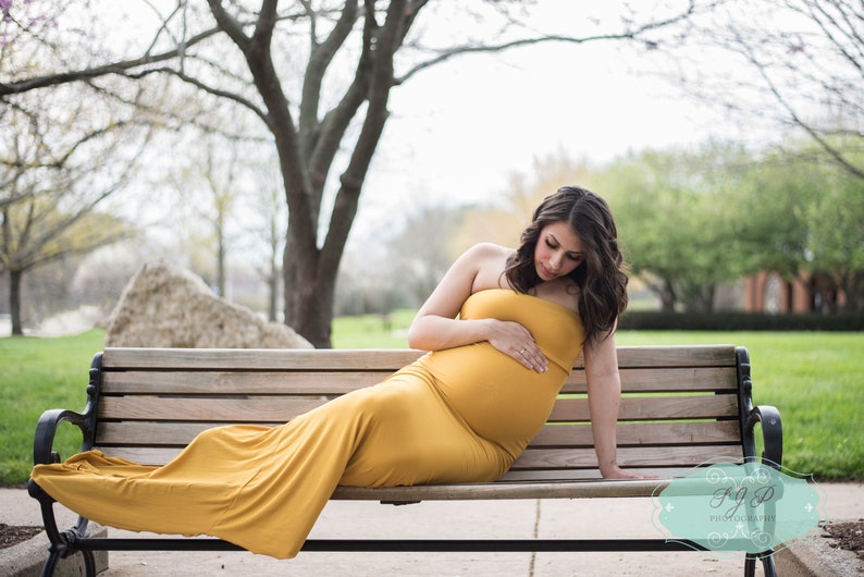 The Aphrodite strapless maternity gown is fitted in a mermaid design that flares at the bottom in a long train. Perfect for special occasions, the soft knit dress hugs your curves and bump in all the right places. Comes in many colors & plus sizes.