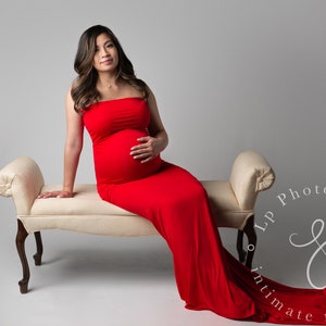 The Aphrodite strapless maternity gown is fitted in a mermaid design that flares at the bottom in a long train. Perfect for special occasions, the soft knit dress hugs your curves and bump in all the right places. Comes in many colors & plus sizes.