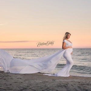 The Odette short-sleeve jersey knit maternity gown features a long chiffon train for maternity photoshoots. The form-fitting bodice with a wide V neckline and sweet off-the-shoulder short sleeves tops a classical empire waistline for a romantic look.