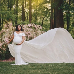 The Odette short-sleeve jersey knit maternity gown features a long chiffon train for maternity photoshoots. The form-fitting bodice with a wide V neckline and sweet off-the-shoulder short sleeves tops a classical empire waistline for a romantic look.
