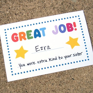 May include: A colorful certificate with a blue dotted border reads "GREAT JOB!" with a rainbow color scheme. The certificate is addressed to Ezra and says "You were extra kind to your sister".