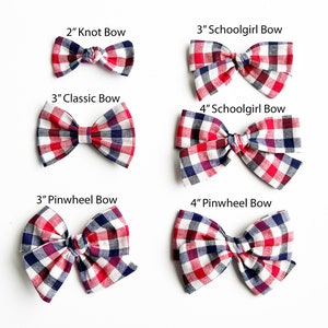 May include: Six red, white and blue gingham hair bows in various sizes and styles. The bows are labelled with their size and style: 2" Knot Bow, 3" Schoolgirl Bow, 3" Classic Bow, 4" Schoolgirl Bow, 3" Pinwheel Bow, and 4" Pinwheel Bow.