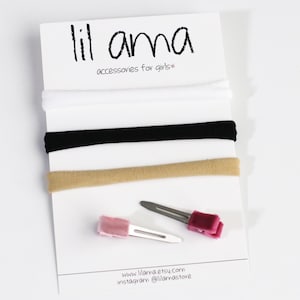 May include: Three elastic headbands in white, black, and beige, and two hair clips with pink and burgundy velvet accents. The text "lil ama accessories for girls*" is printed on a white card.