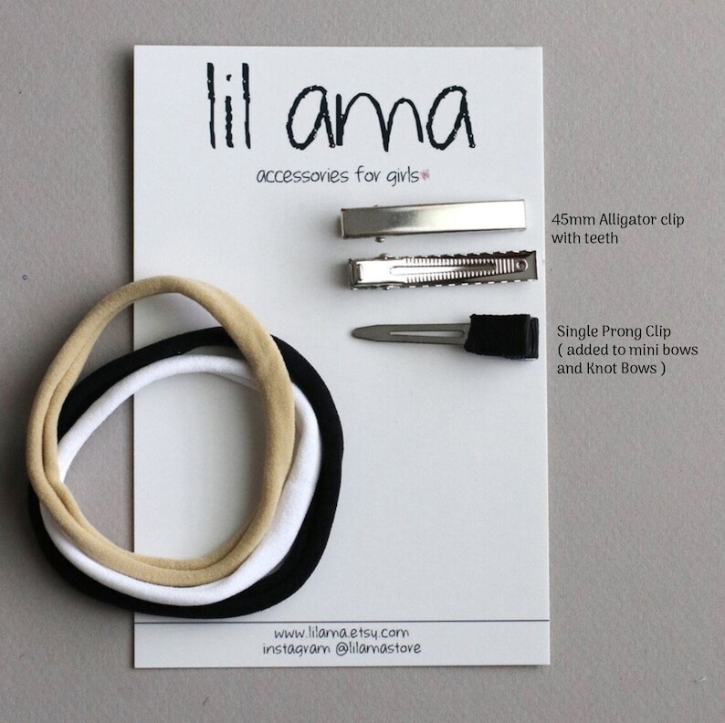 May include: A white card with the text "lil ama accessories for girls" features hair accessories. Includes a 45mm alligator clip, a single prong clip, and three elastic headbands in beige, white, and black. The website and Instagram handle are also visible.