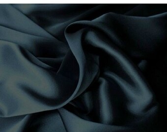 Puede incluir: Primer plano de una tela azul oscuro con un brillo sedoso. La tela está drapeada y doblada, creando sombras y reflejos que enfatizan su textura y fluidez. El efecto general es de lujo y elegancia.