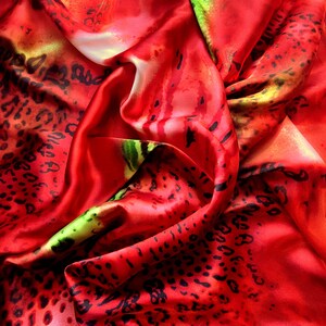 May include: Red satin fabric with a black leopard print pattern. The fabric is draped and folded, creating a textured and luxurious look.
