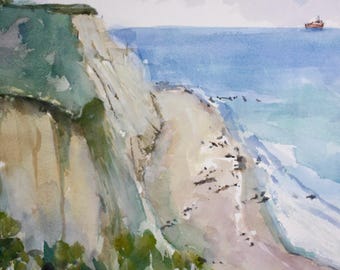 May include: A watercolor painting depicting a coastal scene with a tall cliff topped by a lighthouse. Below the cliff, a sandy beach meets the blue ocean. A small boat and a sailboat are visible on the water. The artist's signature is in the corner.