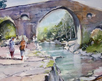 May include: Watercolor painting of an old stone bridge with an arched opening. Two figures walk along the path towards the bridge. The scene includes a river, trees, and a cloudy sky, with the artist's signature in the lower left corner.