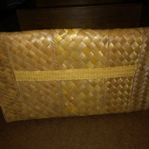 Pu&ograve; includere: Pochette rettangolare in paglia intrecciata. La borsa &egrave; realizzata in paglia marrone chiaro, intrecciata con un motivo a trama di cesto. Una fascia di paglia pi&ugrave; chiara &egrave; intrecciata al centro della borsa.