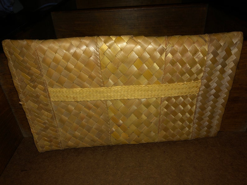 Pu&ograve; includere: Pochette rettangolare in paglia intrecciata. La borsa &egrave; realizzata in paglia marrone chiaro, intrecciata con un motivo a trama di cesto. Una fascia di paglia pi&ugrave; chiara &egrave; intrecciata al centro della borsa.