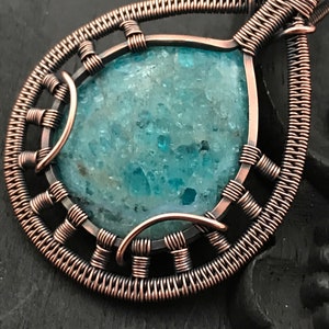 K&ouml;nnte beinhalten: Ein Anh&auml;nger aus Kupferdraht mit einem blaugr&uuml;nen Edelstein mit funkelnder, kristalliner Textur.