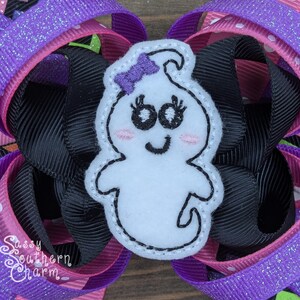 Peut inclure: Un fant&ocirc;me en feutre blanc avec des yeux brod&eacute;s, un sourire et un n&oelig;ud violet. Le fant&ocirc;me est attach&eacute; &agrave; un ruban noir et rose &agrave; pois blancs.