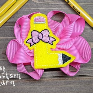Op de afbeelding: Een gele viltstift met een roze strik en zwarte details, op een roze gerimpeld lint. De tekst "Sassy Southern Charm" is zichtbaar onder de stift.