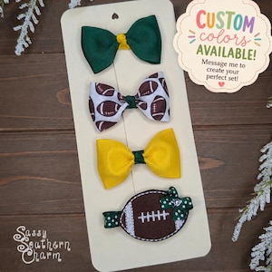 May include: Four hair bows attached to a display card. The top bow is solid dark green, the second features a brown and white football pattern, the third is solid yellow, and the bottom is a brown felt football shape with a small green polka dot bow.