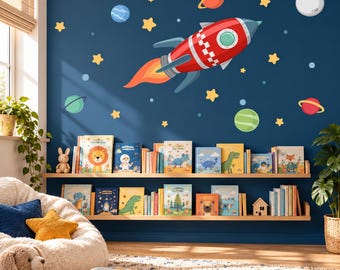 May include: A wall decal set featuring a red and white rocket ship with a fiery orange exhaust, surrounded by various colorful planets, stars, and moons against a dark blue background, applied to a wall above two wooden bookshelves.