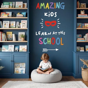 Może przedstawiać: Dziecko siedzi na szarym pufie i czyta książkę w pokoju z niebieskimi ścianami i regałami na książki. Na ścianie znajduje się kolorowy napis "AMAZING KIDS LEARN AT THIS SCHOOL" z czerwoną maską superbohatera i strzałką wskazującą w prawo.