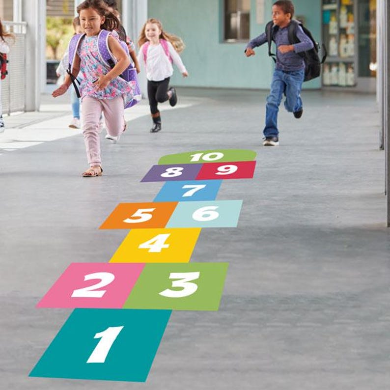 K&ouml;nnte beinhalten: Ein farbenfrohes H&uuml;pfspiel-Raster auf einer Betonoberfl&auml;che, mit den Zahlen 1 bis 10 in Wei&szlig;. Kinder rennen und spielen in der N&auml;he des H&uuml;pfspiels. Die Quadrate sind in verschiedenen Farben gehalten, darunter T&uuml;rkis, Rosa, Gr&uuml;n, Gelb, Orange und Lila.