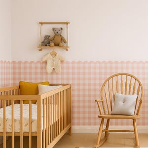 Könnte beinhalten: Ein Kinderzimmer mit einem Holzbett, einem Schaukelstuhl und einem Regal mit Teddybären. Die Wände sind mit einem rosa-weißen Vichy-Muster verziert. Ein cremefarbener Strampler hängt an einem Holzkleiderbügel. Gelbe und cremefarbene Kissen liegen im Bett.