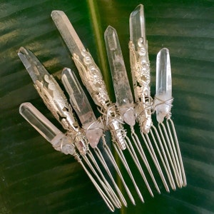 May include: Set of seven silver hair combs with clear quartz crystal tips. The combs are designed with wire wrapped crystal points and have a silver finish.