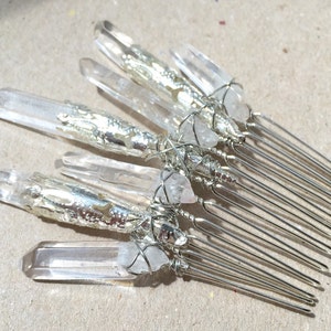 May include: Silver hair comb with clear quartz crystals wrapped in silver wire. The comb has a silver finish and is decorated with clear quartz crystals.
