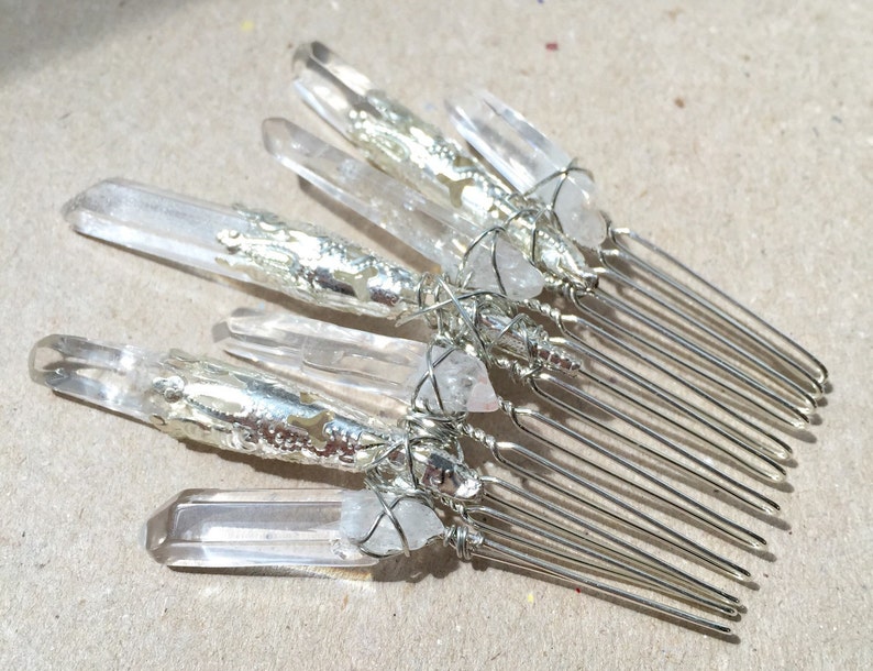 May include: Silver hair comb with clear quartz crystals wrapped in silver wire. The comb has a silver finish and is decorated with clear quartz crystals.