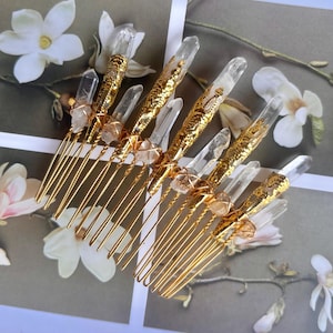 May include: Gold-toned hair combs adorned with clear quartz crystals and decorative gold accents. The combs feature multiple tines and are embellished with natural crystal formations, ideal for bridal or special occasion hairstyles.