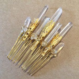May include: Gold hair comb with clear quartz crystals wrapped in gold wire. The comb has seven tines.