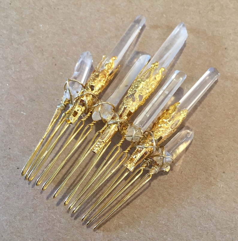 May include: Gold hair comb with clear quartz crystals wrapped in gold wire. The comb has seven tines.