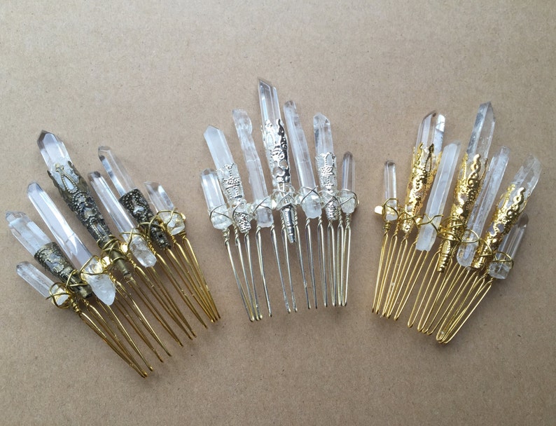 May include: Three gold hair combs with clear quartz crystals and ornate metal accents. The crystals are wrapped in gold wire.