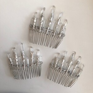 May include: Three silver hair combs with clear quartz crystal accents. The crystals are arranged in a fan shape and attached to the comb with silver wire. The combs are on a white background.