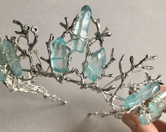 May include: A silver wire crown with branches and light blue crystal points.