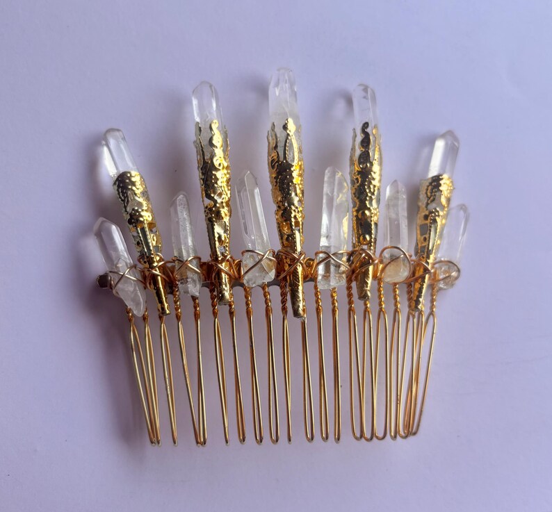 May include: A gold-colored hair comb adorned with clear quartz crystals. The comb features a series of gold-toned teeth, with the crystals arranged along the top. Some crystals are encased in gold filigree.