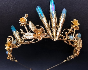May include: A gold wire crown with blue iridescent crystals and gold flowers. The crown is made of wire and has a delicate, whimsical design.